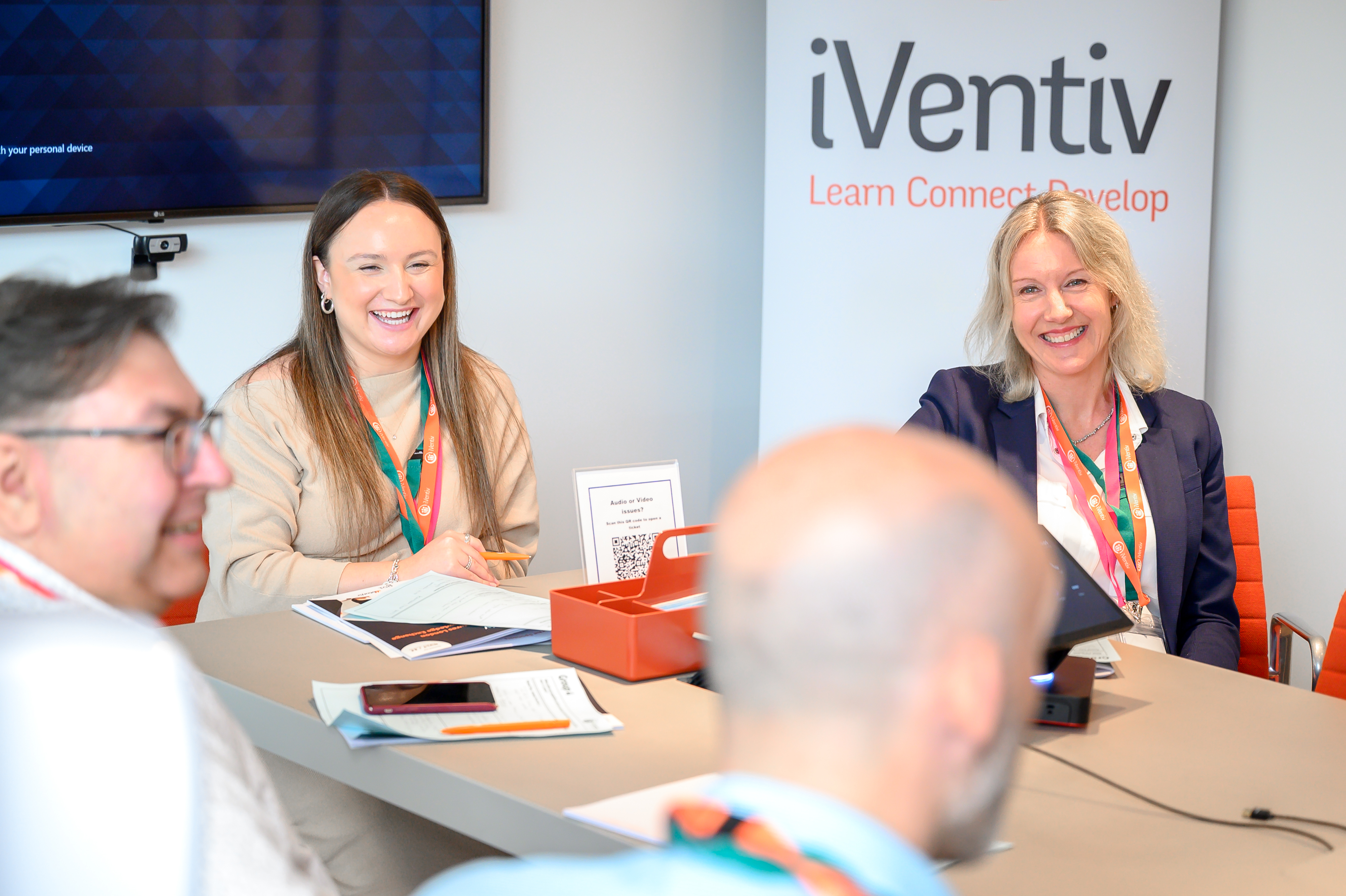A group of people sat round a table smiling at an iVentiv event